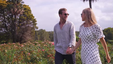 woman and man skipping together in gorgeous rose garden park - flowers