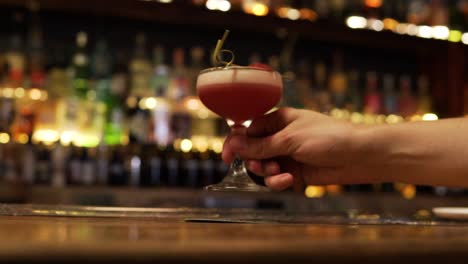cropped view of a person taking a glass of a cocktail drink in a bar. selective focus shot