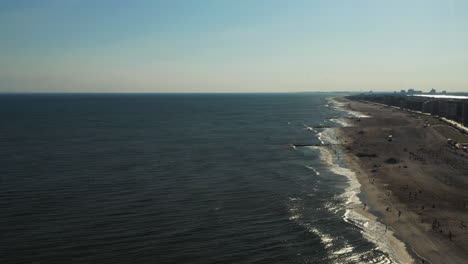 aerial pull away over the ocean with the shoreline on the right side of the shot