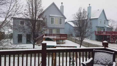 snow falling in a backyard looking out from deck