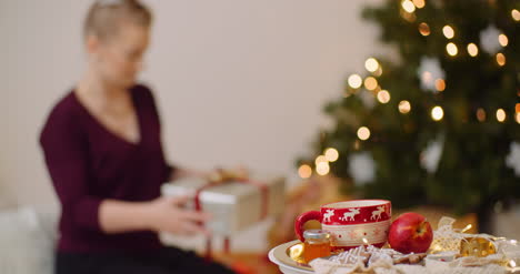 Mujer-Con-Caja-De-Regalo-Y-Posicionamiento-Bajo-El-árbol-De-Navidad-1