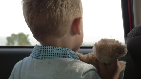 child traveling in car with favourite teddy bear