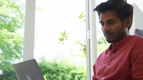 close up of man working from home sitting on floor in lounge using laptop