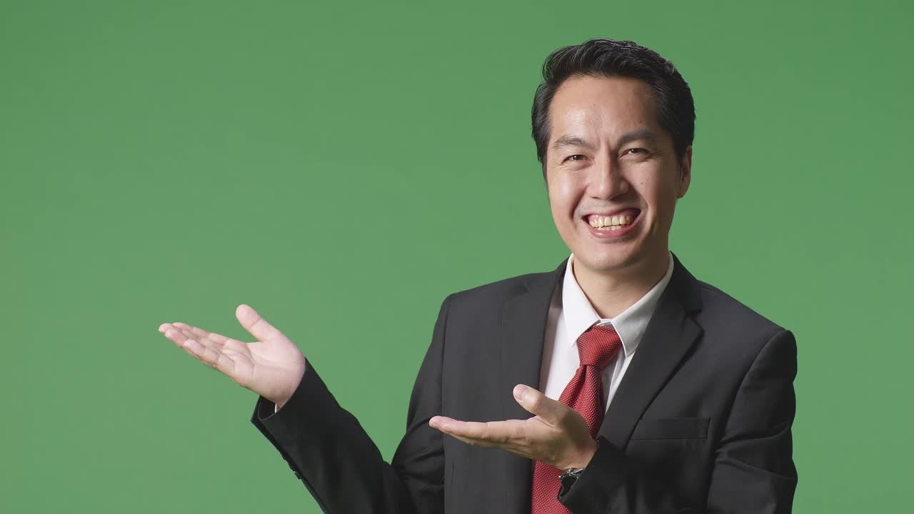 녹색 스크린 에 서 있는 한 아시아인 사업가 가 열린 손바닥 을 보여 준다