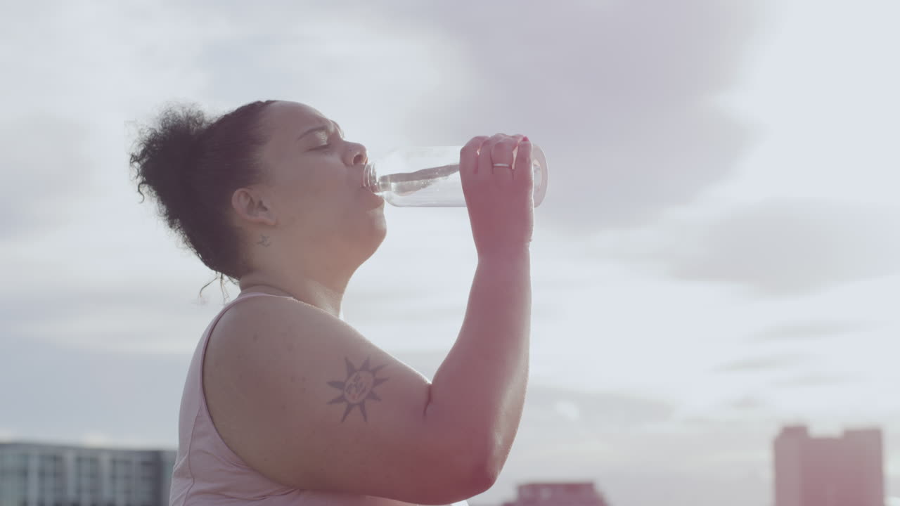 Femme taille plus buvant de l'eau dans une bouteille