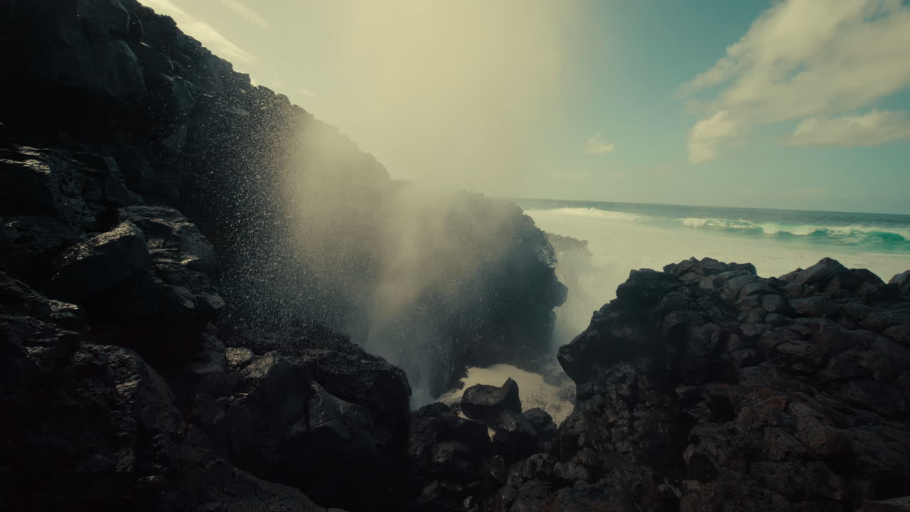 Powerful ocean waves crashing against volcanic rock formations, creating a blowhole