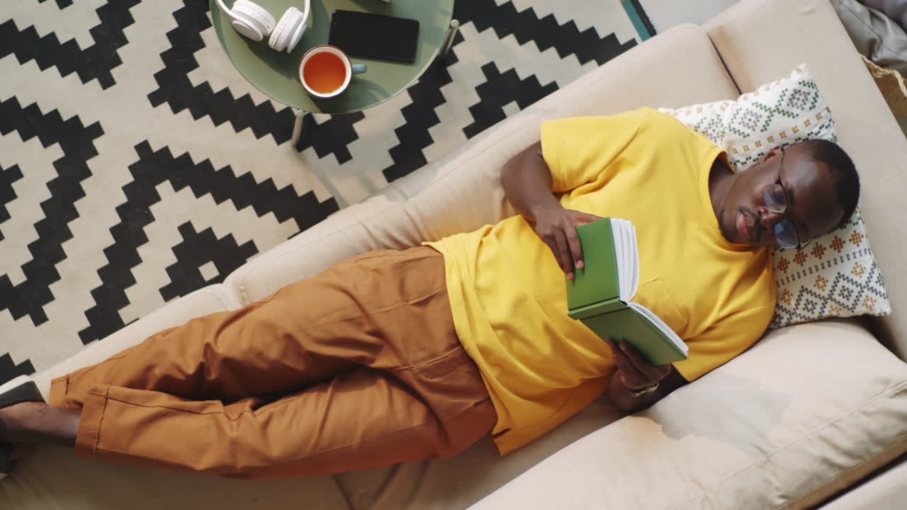 Afro-American Man Reading Book on Sofa