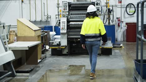 back view of female machine operator walking at factory