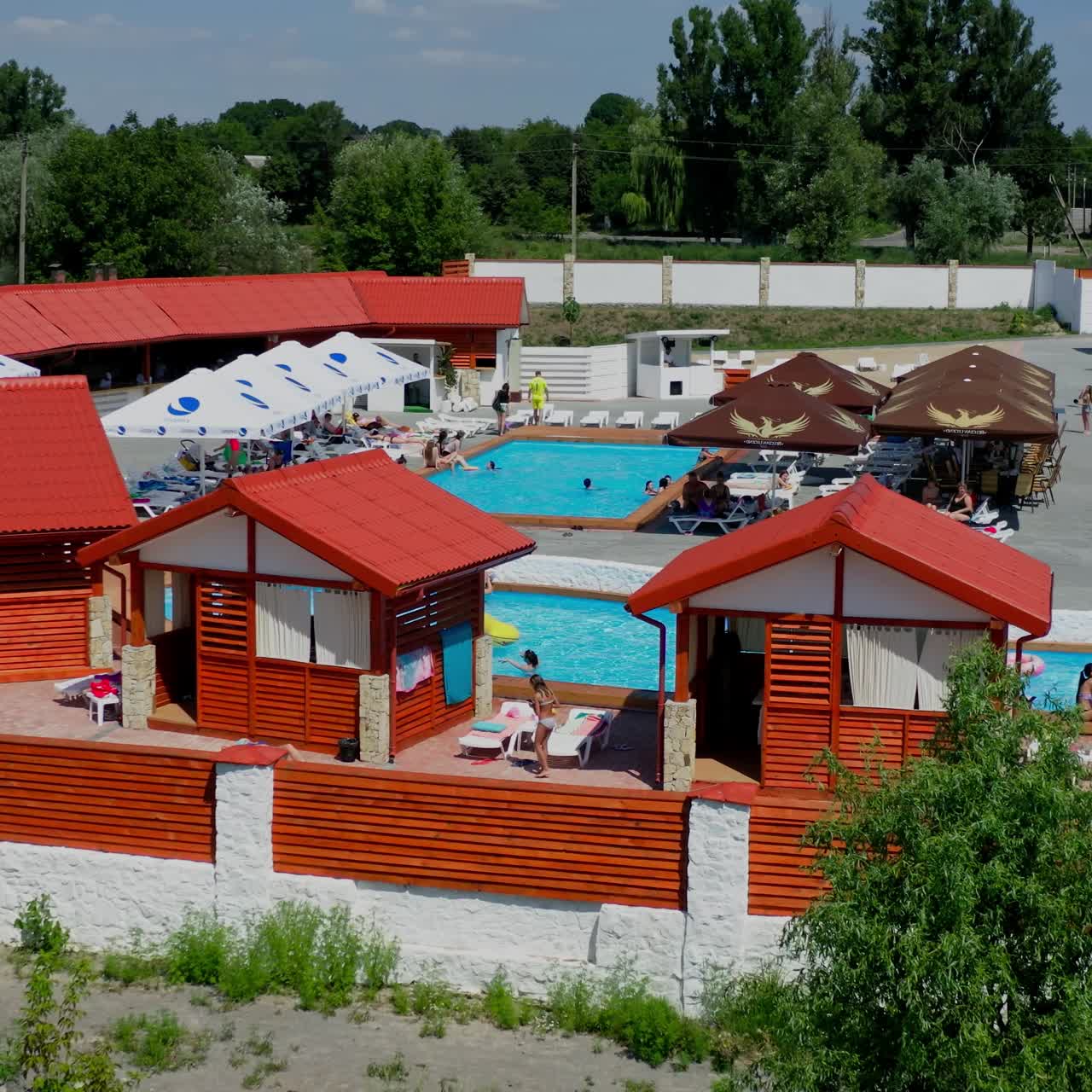 Freibad auf dem Gelände eines Landresorts. Schöner Fluss auf dem Land. Kleine Häuser und offener Pool. Video von oben.