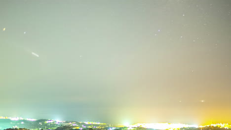 timelapse shot over the town of malaga, spain on a dark starry night with port lights shinning brightly