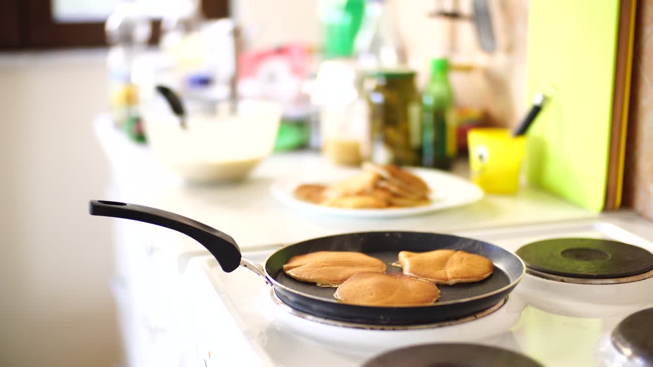 primer plano de tres panqueques dorados en una sartén, vapor blanco claro.