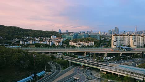 aerial view of seocho-gu umyeon tunnel entrance with urban skyline, samsung research and development center, and lotte tower in the distance at sunset, seoul, south korea
