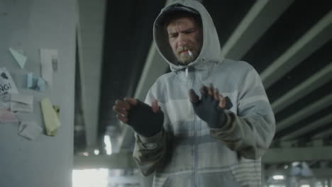 homeless man smoking cigarette near fire barrel