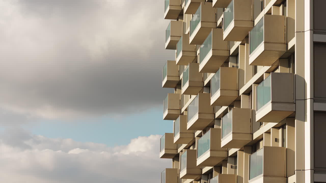 Residential tower with modular balconies and dramatic cloud motion in architectural timelapse