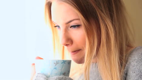 attractive blonde wearing winter clothes drinking coffee