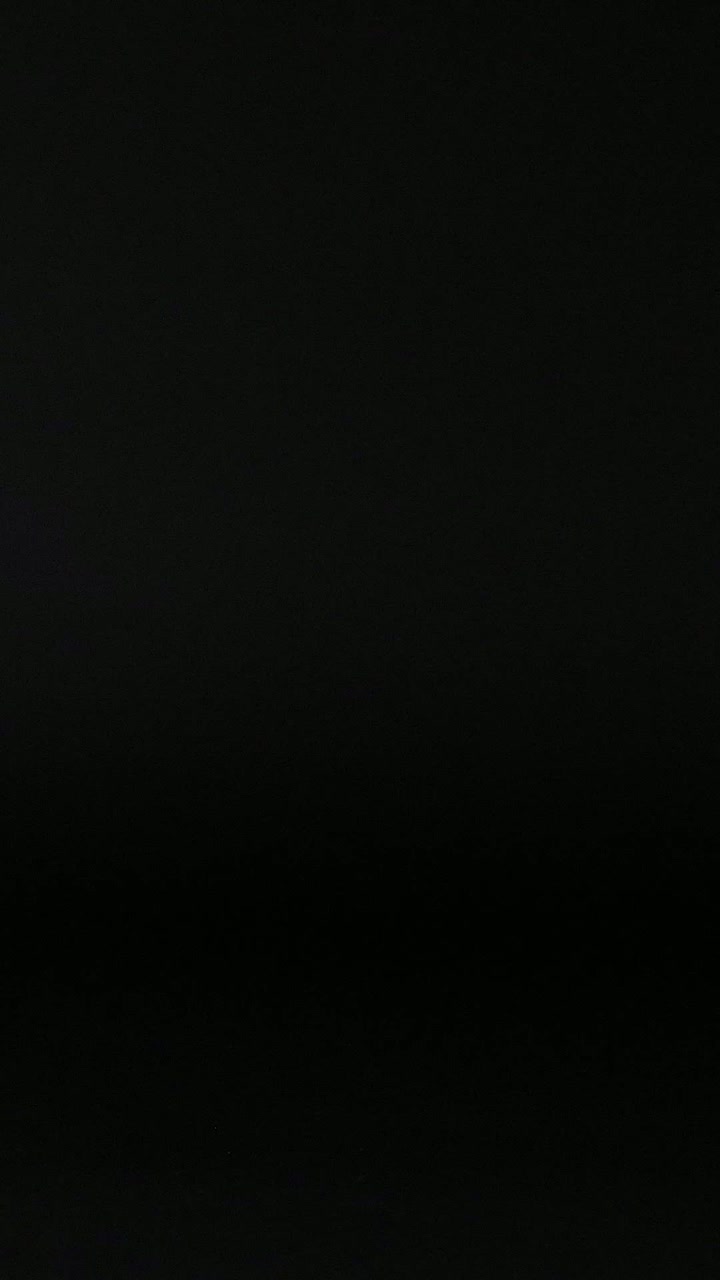 A tennis ball moves across a dark background