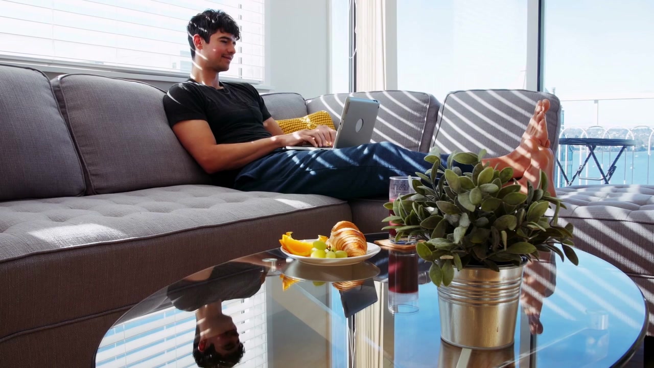 Man reclining sofa typing, starting white frame with binary overlay over laptop for remote work
