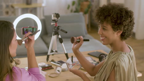 two female beauty bloggers recording video together at home