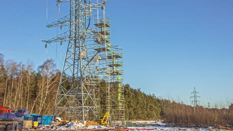 Statische-Aufnahme-Von-Versorgungsarbeitern,-Die-Tagsüber-Einen-Hohen-Strommast-Von-Der-Verlegung-Von-Stromleitungen-In-Ländlicher-Umgebung-Erklimmen