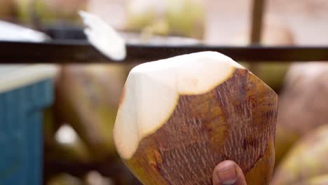 toma cercana del hombre cortando un coco del agua con un cuchillo grande, salpicando el agua en cámara lenta