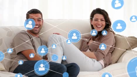 Animation-of-network-of-profiles-over-portrait-of-biracial-couple-smiling-sitting-on-couch-at-home
