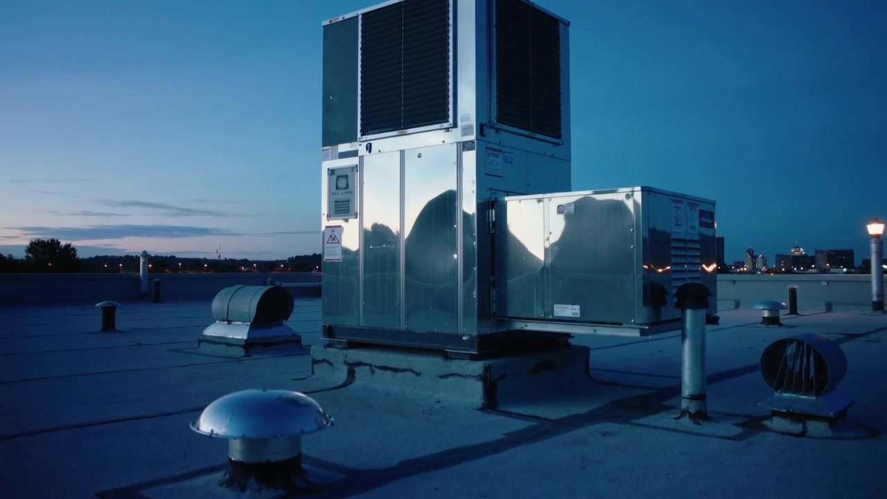 Pushing camera in slow pan across rooftop, revealing reflective HVAC unit, showing dusk reflections