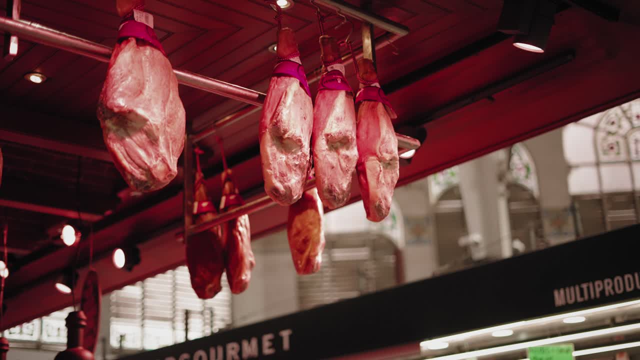 Cured Iberian Hams Hanging at a Busy Valencia Market Stall