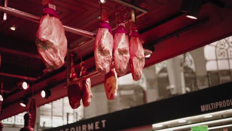 cured iberian hams hanging at a busy valencia market stall