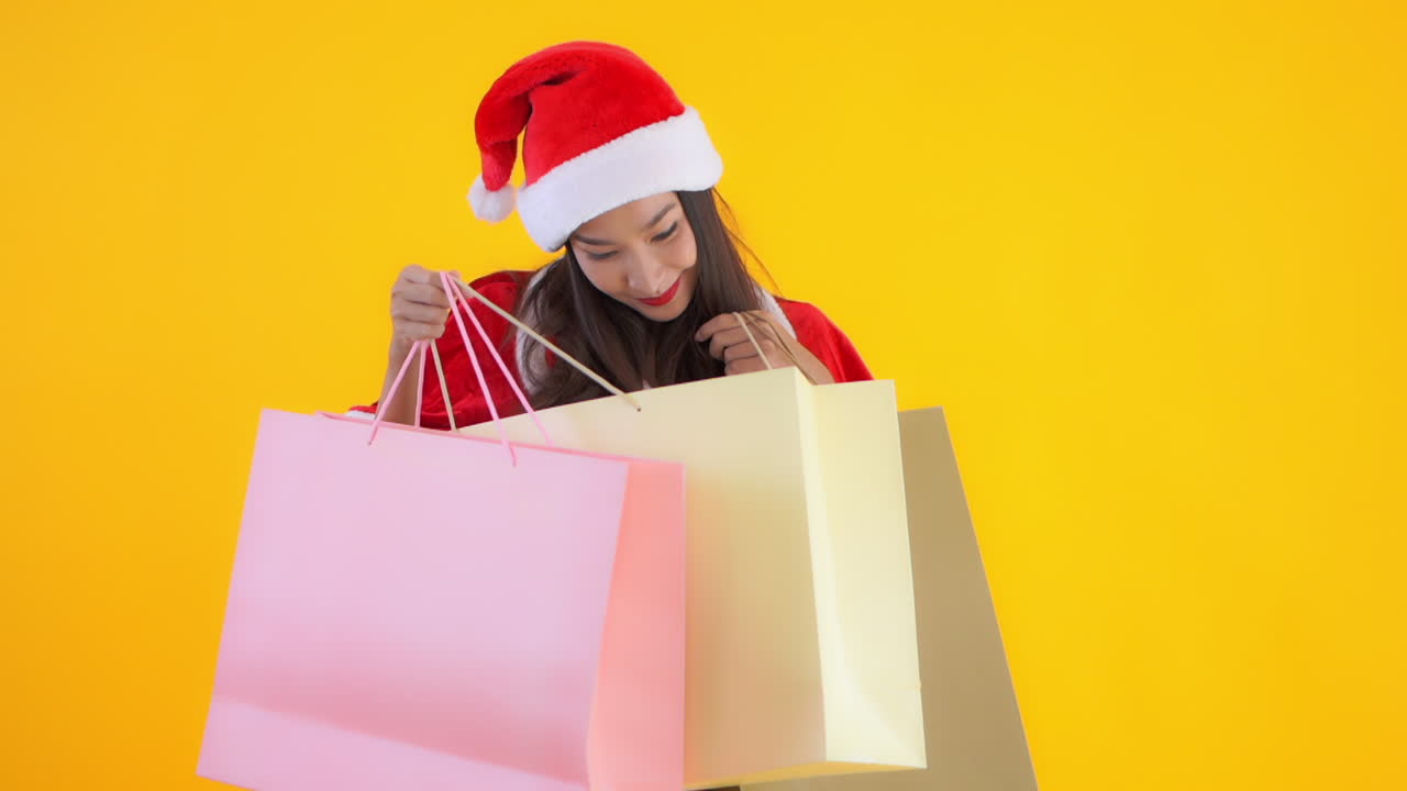 Attractive woman in Christmas costume is handed large colorful paper bags and looks inside smiling. Christmas shopping, order delivery, over spending, holiday debt concept