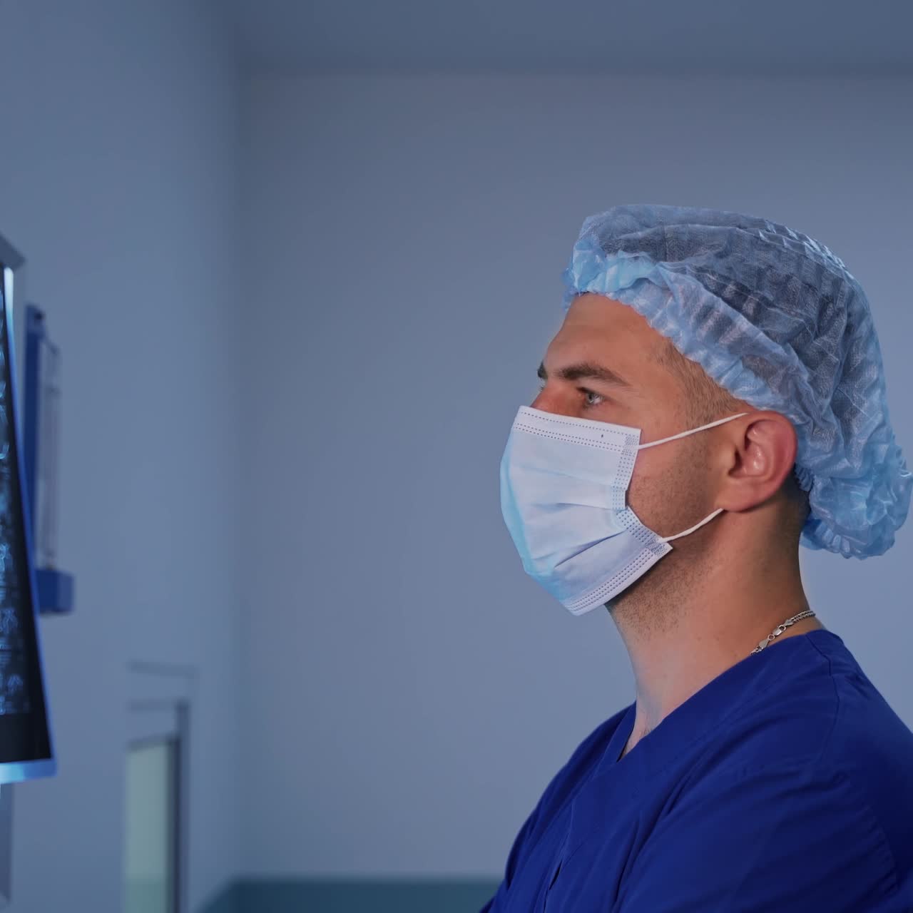 Male medical specialist studying x-ray. Profile of a young doctor in mask examines the x ray photograph of a patient in clinic.