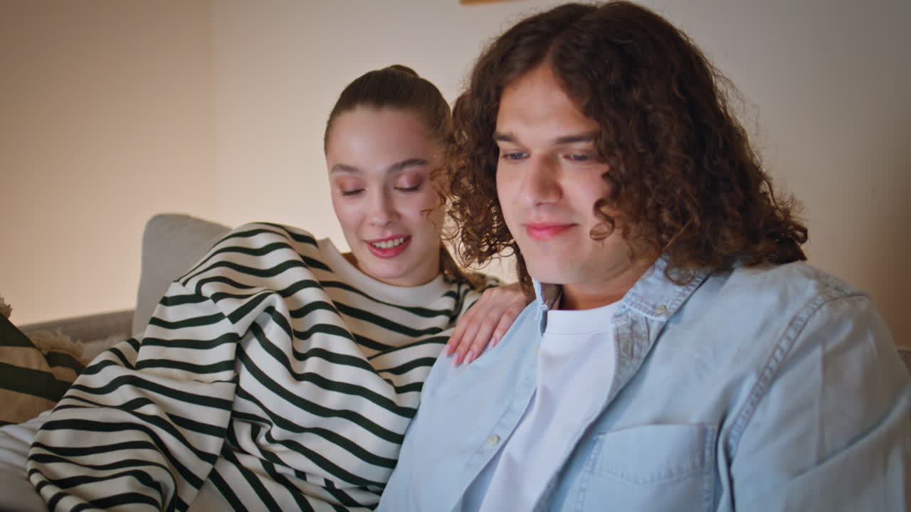 Couple watching online game laptop sitting comfortable home living room closeup
