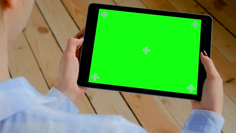 woman looking at tablet computer with blank green screen - chroma key concept