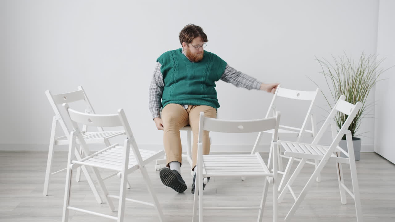 Man Sitting in a Circle of Chairs