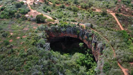 drone aérien s'inclinant vers le haut et travelling hors de l'entrée de la grotte de lapa doce avec une forêt tropicale autonome en dessous dans le parc national de la chapada diamantina à bahia, au nord-est du brésil