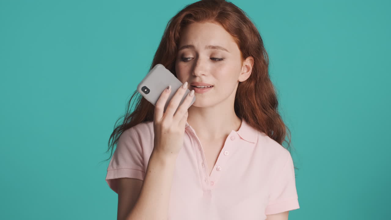 рыжая девушка перед камерой на бирюзовом фоне.