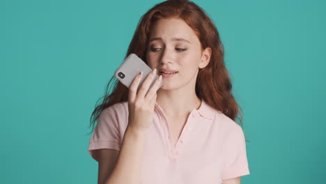 redheaded girl in front of camera on turquoise background.