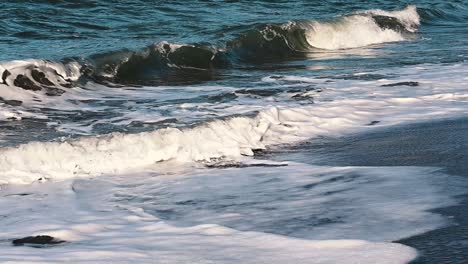 waves from the sea rooling at a sandy beach during with an amazing orange glow on the white foam rewinding back to the ocean