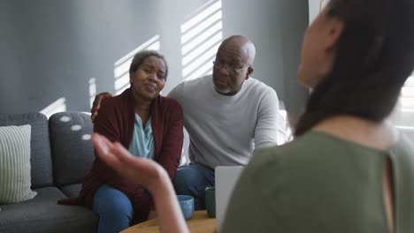 asian female counselor advising to african american senior couple sitting on sofa