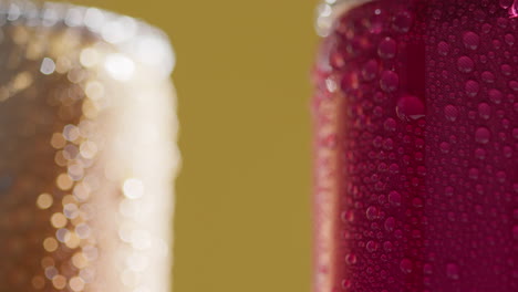 close up of condensation droplets running down takeaway cans of cold beer or soft drinks against yellow background