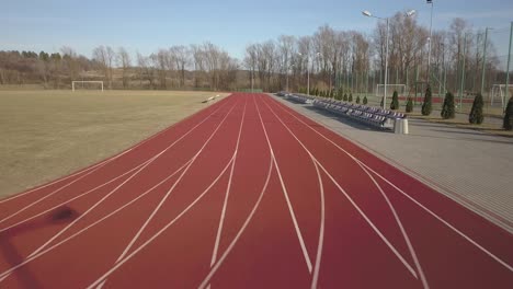 span along the red running track in the stadium. video filming from the air of an element of a sports complex. outdoor coating for sports. the place for competitions in athletics with the height of a