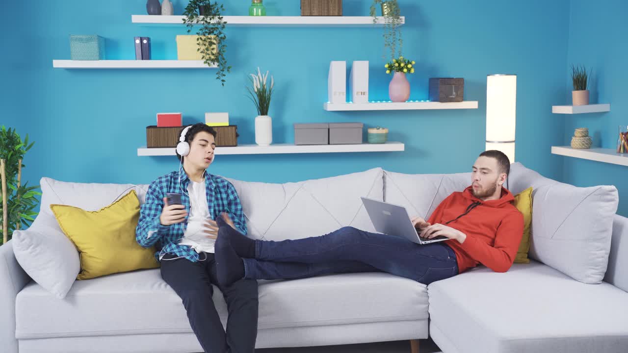 Boy fights competitively on sofa with brother at home because they don't get along