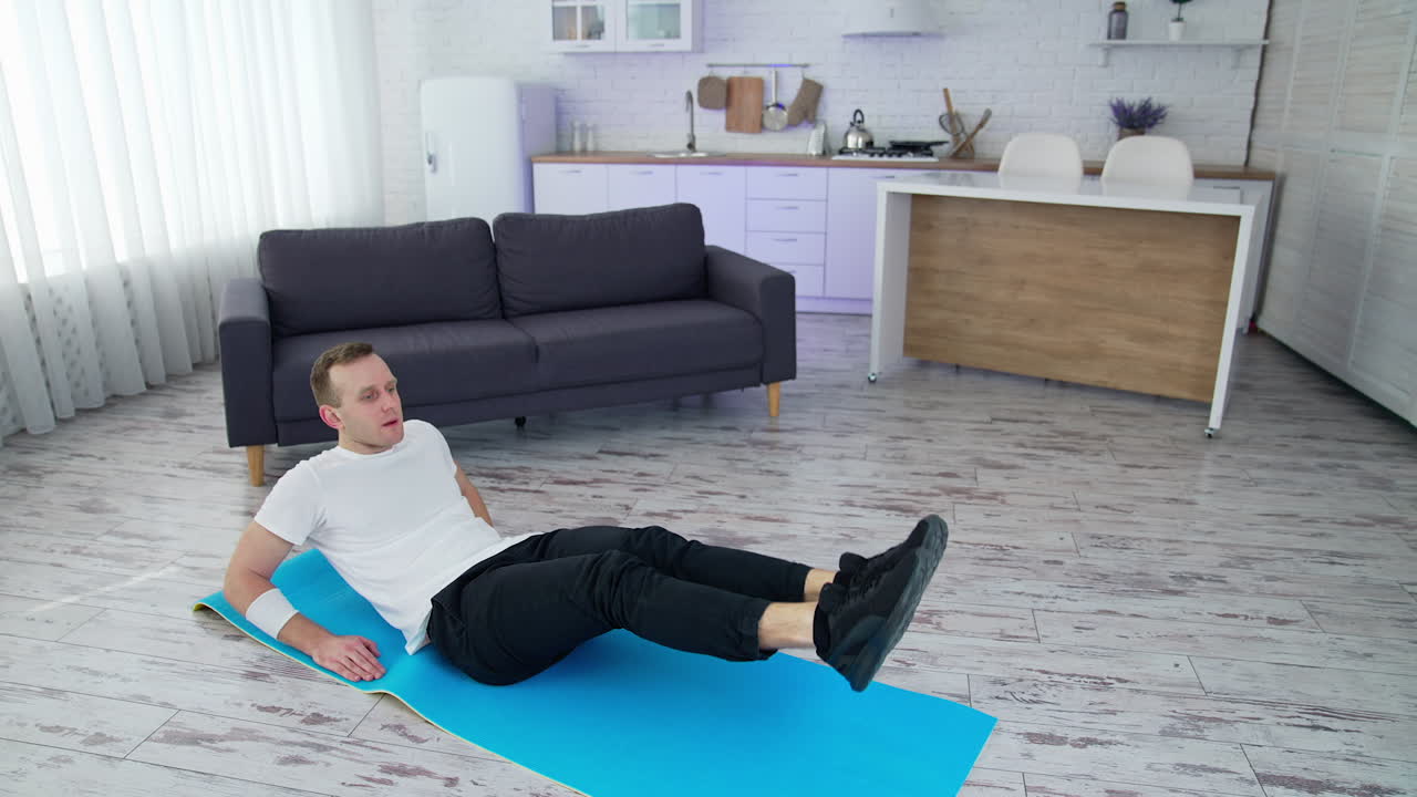 Healthy lifestyle man raising legs while training his body in home. Strong male working out on quarantine. Full length