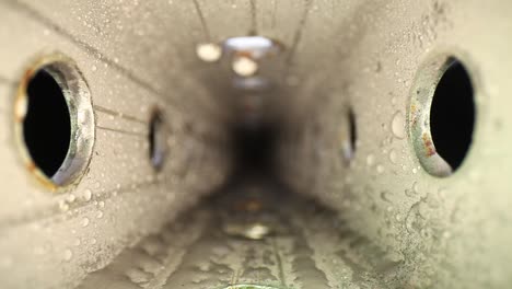 Pushing-into-a-wet-Zinc-Plated-Steel-Perforated-Square-Tube-with-a-wide-angle-macro-probe-lens---showing-texture-on-metal,-holes,-and-water-droplets