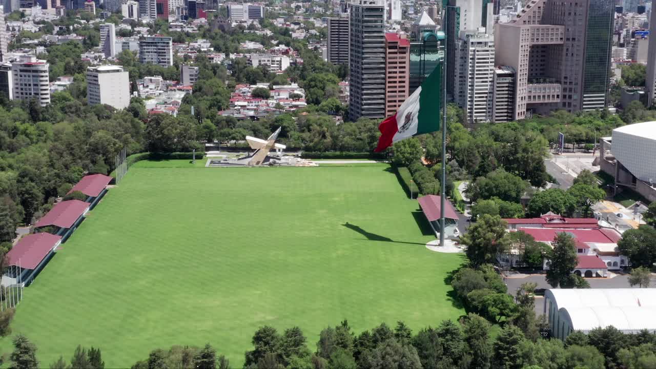 vuelo sobre campo marte vacío, desolado, desierto y cerrado con bandera patriótica mexicana ondeando en el viento, ciudad de méxico, pandemia de covid-19, bloqueo y cuarentena, toma estática de antena aérea