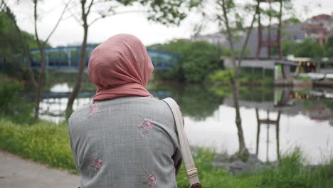 mujer en hijab en el parque junto al río