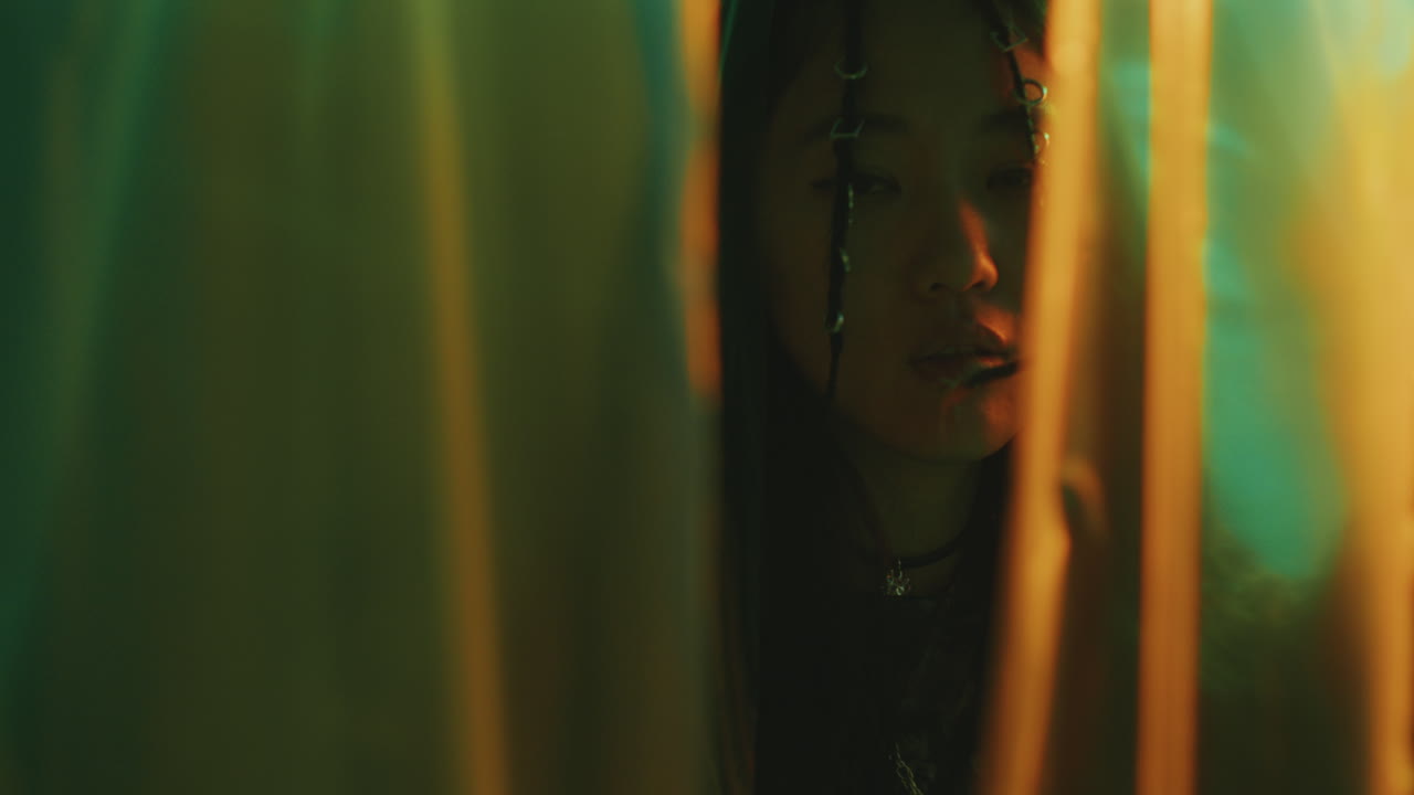 Stylish Asian Woman Walking through Plastic Wrap Curtains in Nightclub