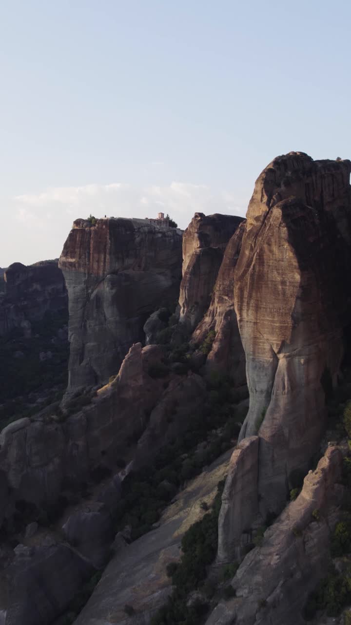 Vertical drone approach highlighting the cliff-top monastery and the towering Meteora rock pillars surrounding it