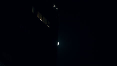 bright moon in the night sky slowly hiding behind building