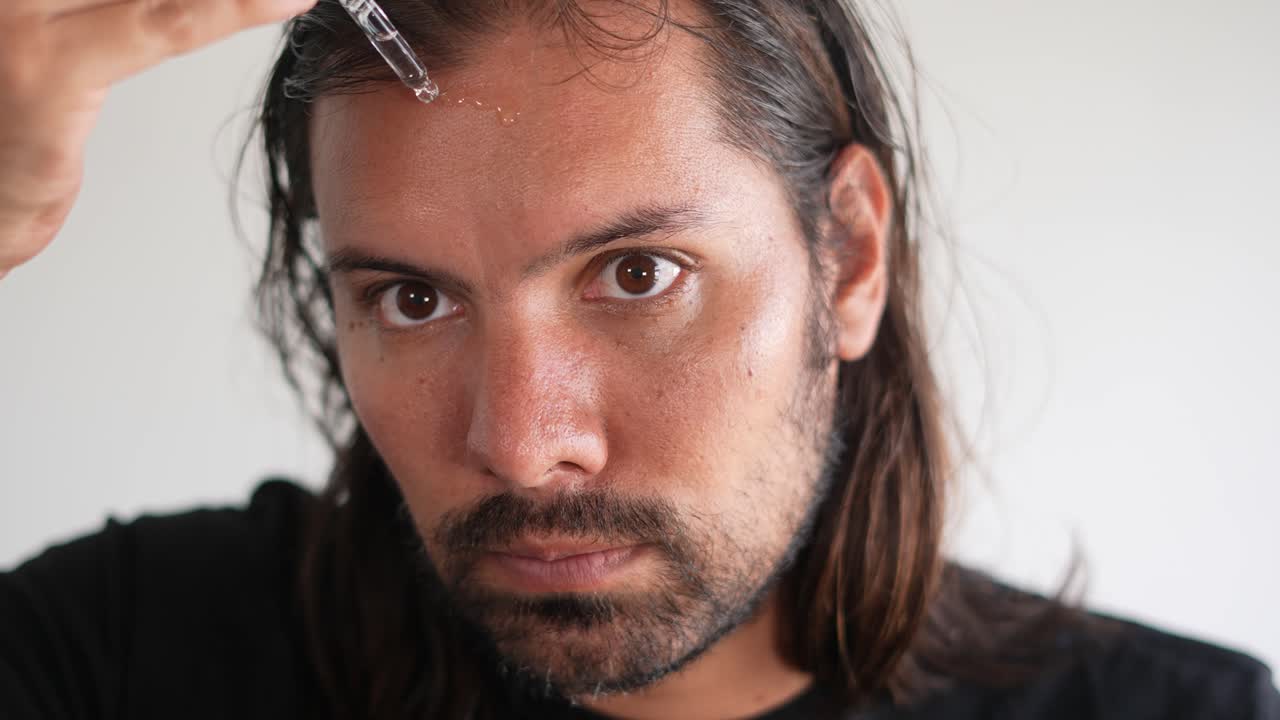 라틴인 남자가 피부에 기름을 넣고 피부 관리합니다.