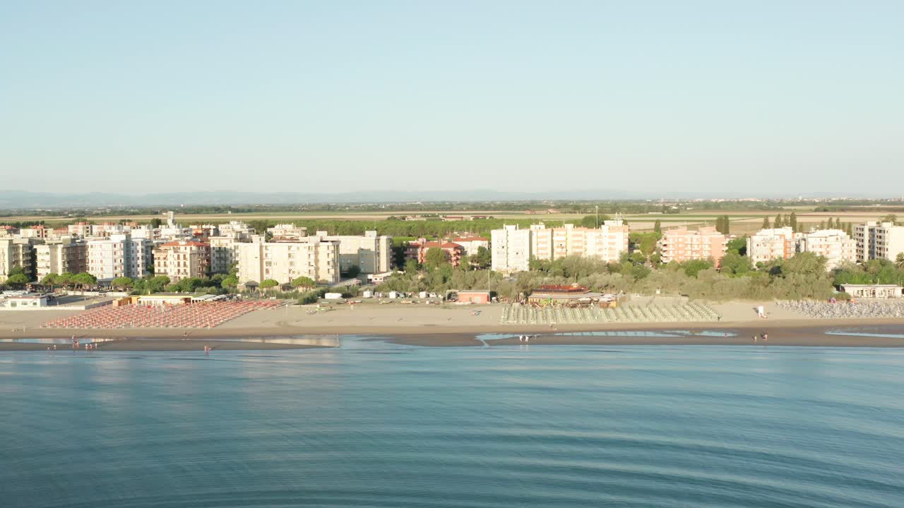 toma aérea de playa de arena con sombrillas y mar adriático, costa típica de emilia romagna